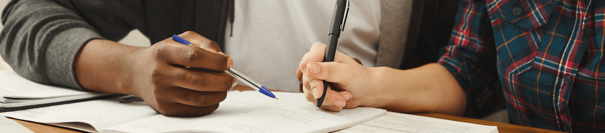 hand of students on desk working on homework