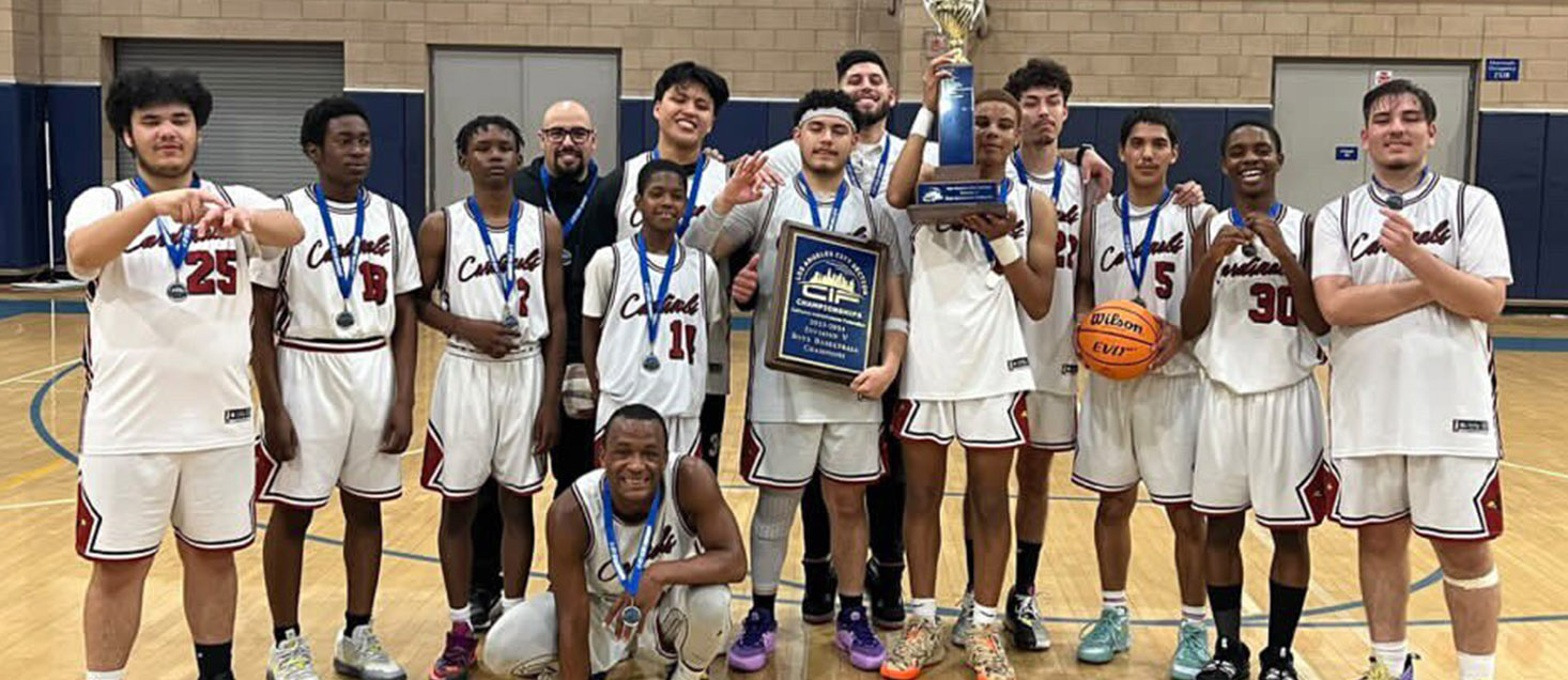 Boys basketball team with coach in the gym wearing blue ribbons and holding trophy