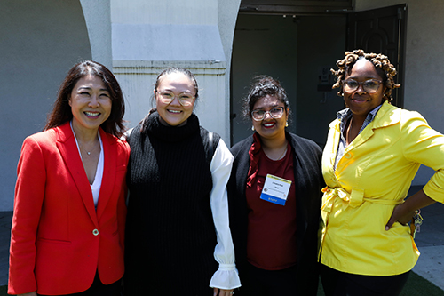 Four women in colorful attire hosting FACE event for families